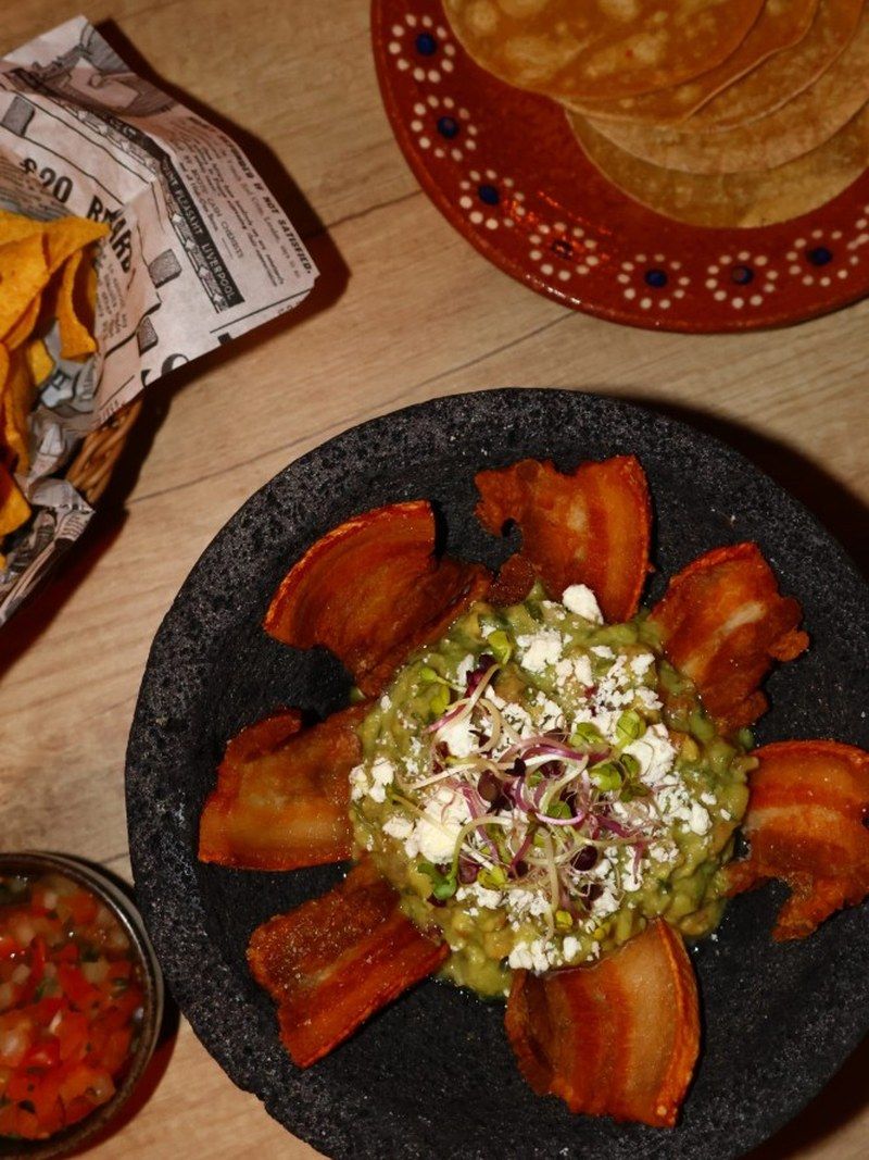 Guacamole servi dans son molcajete, avec chicharrón et tortillas