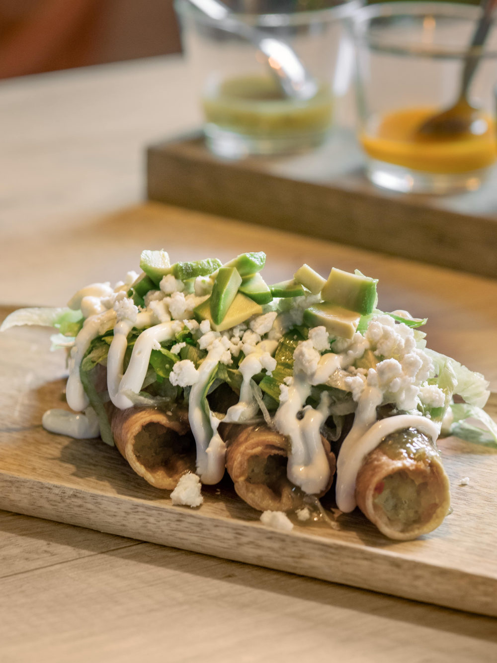 Flautas enrolladas, crema y queso rallado