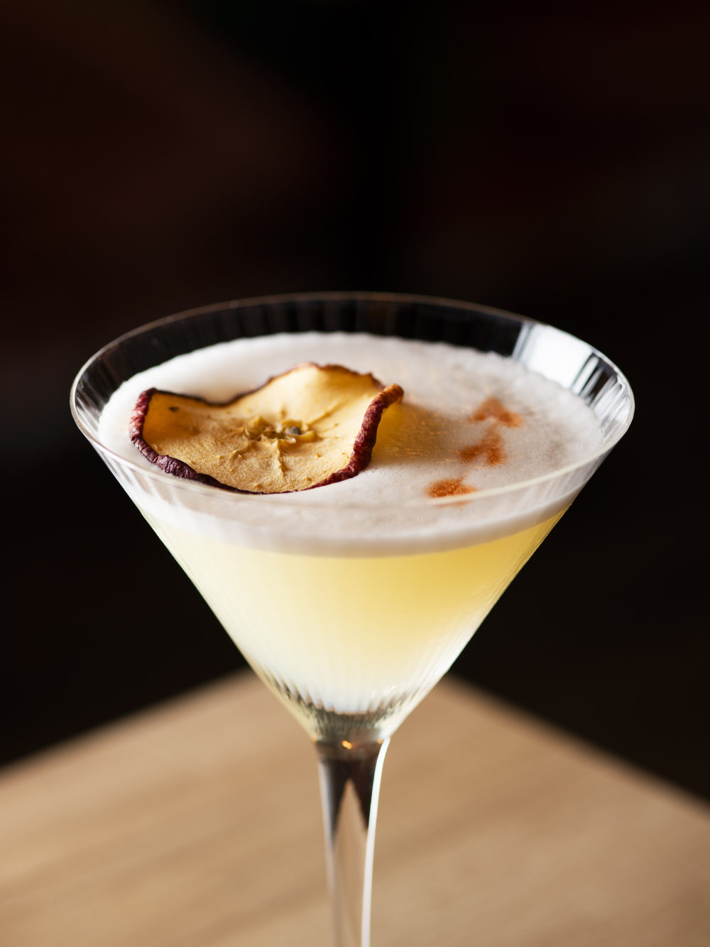 Cocktail servito in coppa da martini, fetta di frutta essiccata